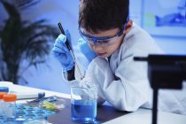 Écolier faisant des expériences scientifiques dans un laboratoire de chimie scolaire . — Photo de stock