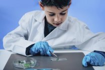 Schoolboy colocando folhas na lâmina do microscópio no laboratório da escola . — Fotografia de Stock