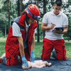 Weibliche Rettungssanitäter cpr Ausbildung mit Instruktor auf Baby-Dummy im Freien. — Stockfoto