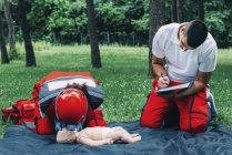 Entrenamiento de RCP paramédico femenino en muñeco de bebé con instructor al aire libre . - foto de stock
