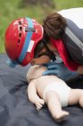 Female paramedic CPR training on baby dummy outdoors. — Stock Photo