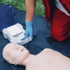 Entrenamiento de desfibrilador paramédico femenino con maniquí al aire libre . - foto de stock