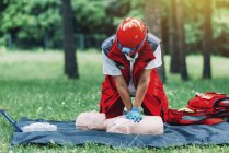 Entrenamiento de RCP paramédico femenino con maniquí al aire libre . - foto de stock