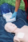 Female paramedic defibrillator training with dummy outdoors. — Stock Photo