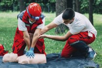 Female paramedic with instructor CPR training on dummy outdoors. — Stock Photo