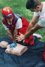 Un instructeur aide une ambulancière paramédicale à suivre une formation en RCR à l'extérieur . — Photo de stock