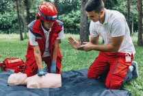 Paramédica femenina con instructor de entrenamiento de RCP en maniquí al aire libre . - foto de stock