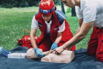 Feminino paramédico e instrutor de treinamento de RCP em dummy ao ar livre . — Fotografia de Stock