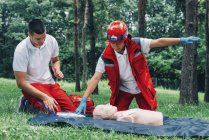 Female paramedic and instructor CPR training on dummy outdoors. — Stock Photo