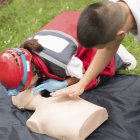 Instructor ayudando a paramédica femenina con entrenamiento de RCP al aire libre . - foto de stock