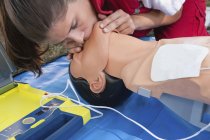 Female paramedic practicing mouth to mouth CPR training outdoors. — Stock Photo