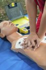 Entraînement de défibrillateur paramédical féminin avec mannequin à l'extérieur . — Photo de stock
