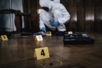 Marcadores de cena de crime e especialista forense coletando amostras de sangue em segundo plano . — Fotografia de Stock
