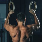 Strong muscular man exercising on gymnastic rings. — Stock Photo