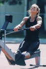 Woman performing rowing machine workout at stadium. — Stock Photo