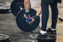 Cropped view of male athlete changing weights on barbell. — Stock Photo