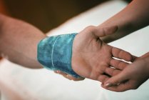 Руки женщины-терапевта накладывают пакет со льдом на болезненное запястье мужчины-спортсмена
. — стоковое фото