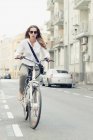 Female office worker using e-bike on road to work in city. — Stock Photo