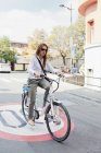 Donna d'affari in bicicletta elettrica in strada
. — Foto stock