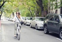 Frau fährt Elektro-Fahrrad auf Stadtstraße. — Stockfoto