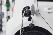 Electric car charging with cable at service station. — Stock Photo