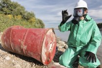 Pollution control inspector looking at sample of leaked chemical next to river. — Stock Photo