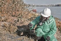 Inspecteur de lutte contre la pollution prélever un échantillon de boue dans le champ par lac . — Photo de stock