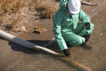 Water quality inspector taking sample of water at suspected pollution site — Stock Photo