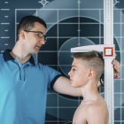 Physical therapist measuring height of teenage boy. — Stock Photo