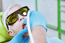 Dentist performing laser teeth whitening at female patient at dental clinic. — Stock Photo