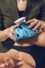 Mãos de fisioterapeuta segurando saco de gelo azul no ombro doloroso da esportista . — Fotografia de Stock