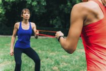 Female friends exercising with elastic band in park. — Stock Photo