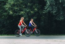 Duas mulheres adultas médias pedalando juntas no parque . — Fotografia de Stock