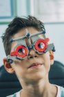 Хлопчик початкового віку в окулярах офтальмології під час огляду очей у клініці . — стокове фото