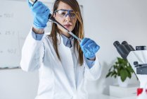 Técnico femenino de laboratorio con micropipeta científica . - foto de stock