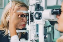 Ophthalmologist examining patient with slit lamp and magnifying lens. — Stock Photo