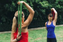 Frauen trainieren mit Gummibändern im grünen Park. — Stockfoto
