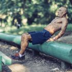 Ajuste hombre mayor haciendo ejercicio sobre equipos de madera en el parque . - foto de stock