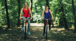 Mujer riding bikes together in sunny park . - foto de stock