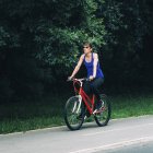 Mid adult woman riding bike in summer park. — Stock Photo