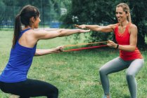 Women exercising with elastic band in summer park. — Stock Photo