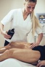 Fisioterapeuta massagista homem e aplicação de óleo de massagem . — Fotografia de Stock
