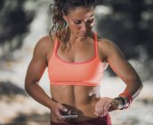 Mujer comprobando el progreso en smartwatch después de entrenar al aire libre . - foto de stock