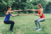 Donne che si allenano con elastico nel parco verde . — Foto stock