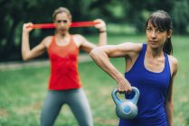 Mujeres haciendo ejercicio al aire libre con pesas y banda elástica . - foto de stock