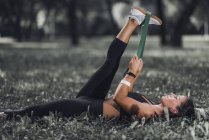 Athletic woman stretching with elastic band after exercise in park. — Stock Photo