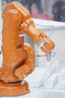 Orange industrial robotic arm working at high tech factory. — Stock Photo
