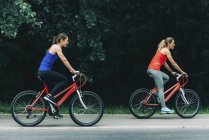 Amigos do sexo feminino andar de bicicleta juntos no parque . — Fotografia de Stock