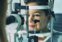 Garçon d'âge élémentaire soumis à un examen de la vue avec lampe à fente dans une clinique d'ophtalmologie . — Photo de stock
