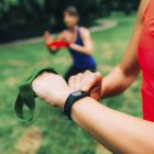 Mulher verificando o progresso no smartwatch após treinamento ao ar livre com amigo . — Fotografia de Stock